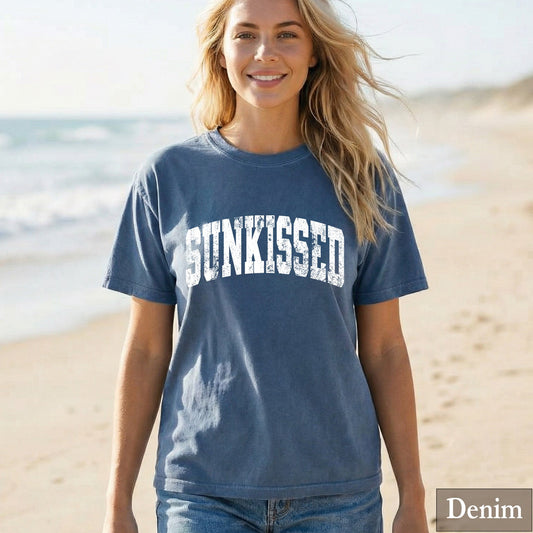 Woman wearing a denim 'SUNKISSED' t-shirt on a beach