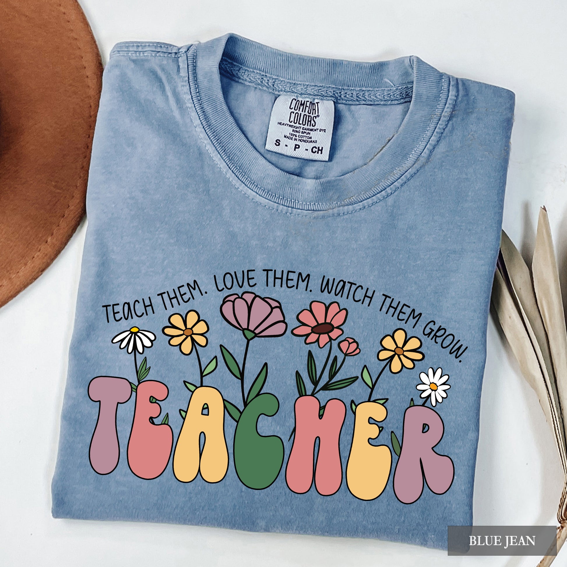 Blue denim shirt with colorful text and flowers on a white background