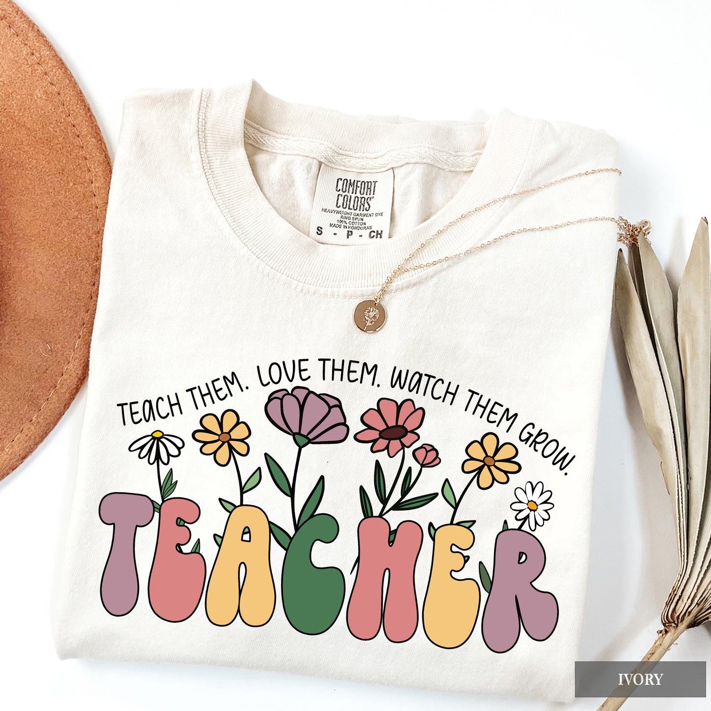 White sweatshirt with colorful 'TEACHER' text and floral design on a white background