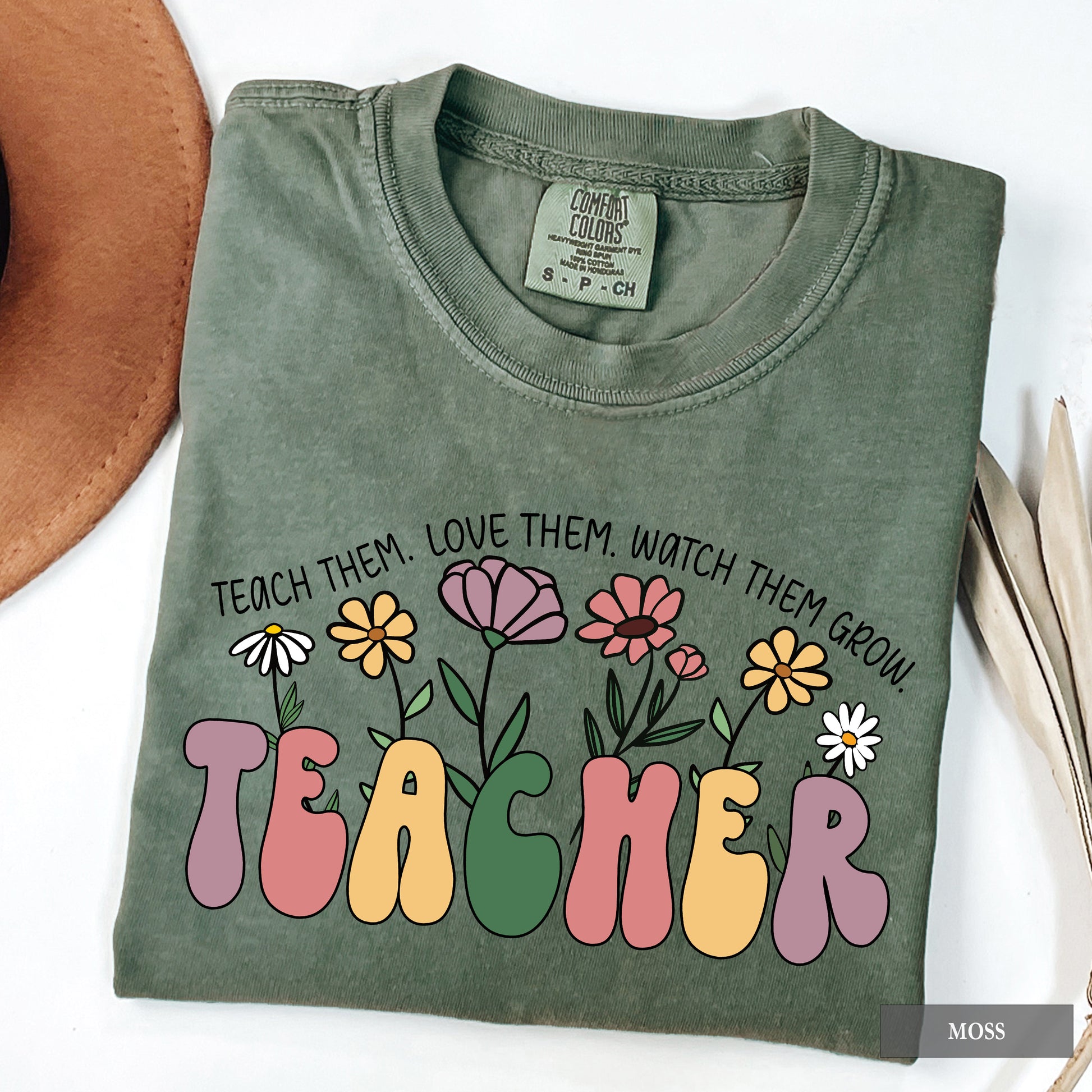 Folded green t-shirt with floral design and text on a white background