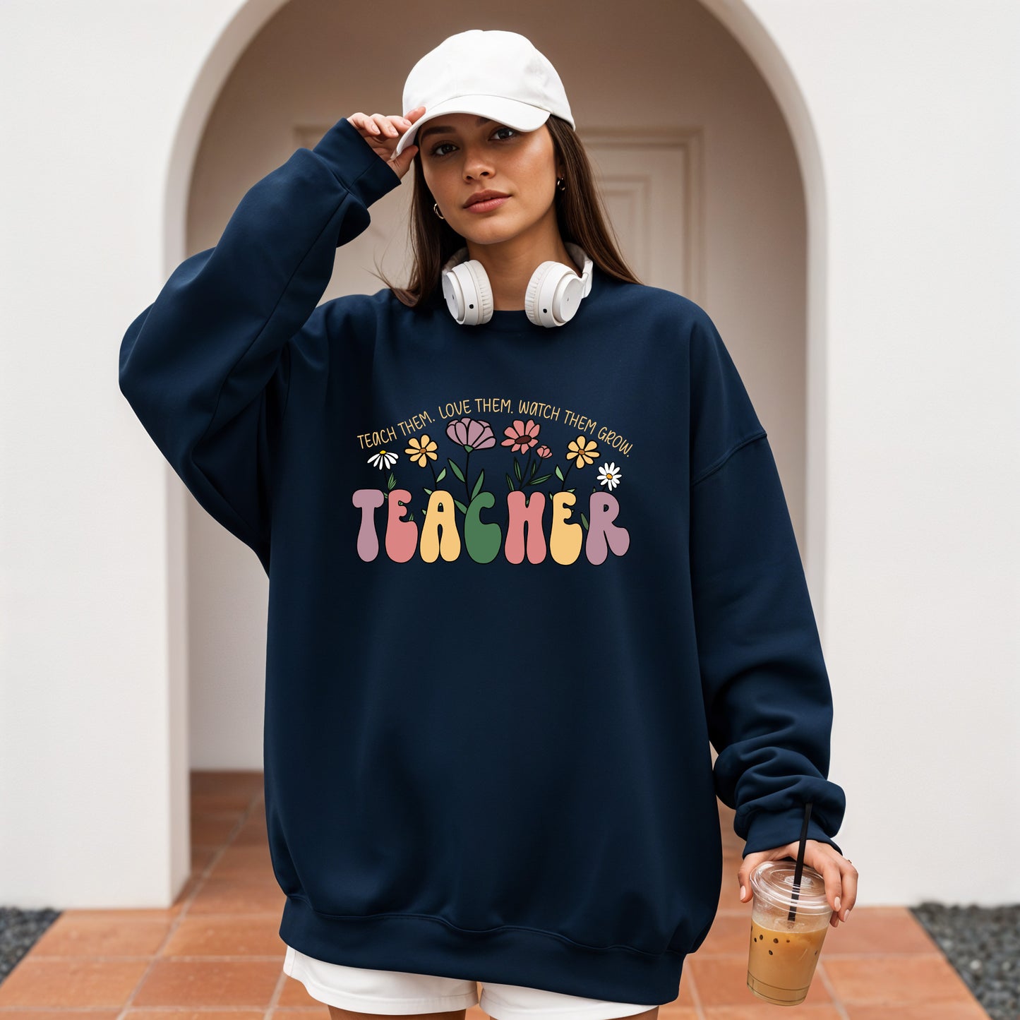 Person wearing a navy blue sweatshirt with 'TEACHER' printed on it, holding a drink.