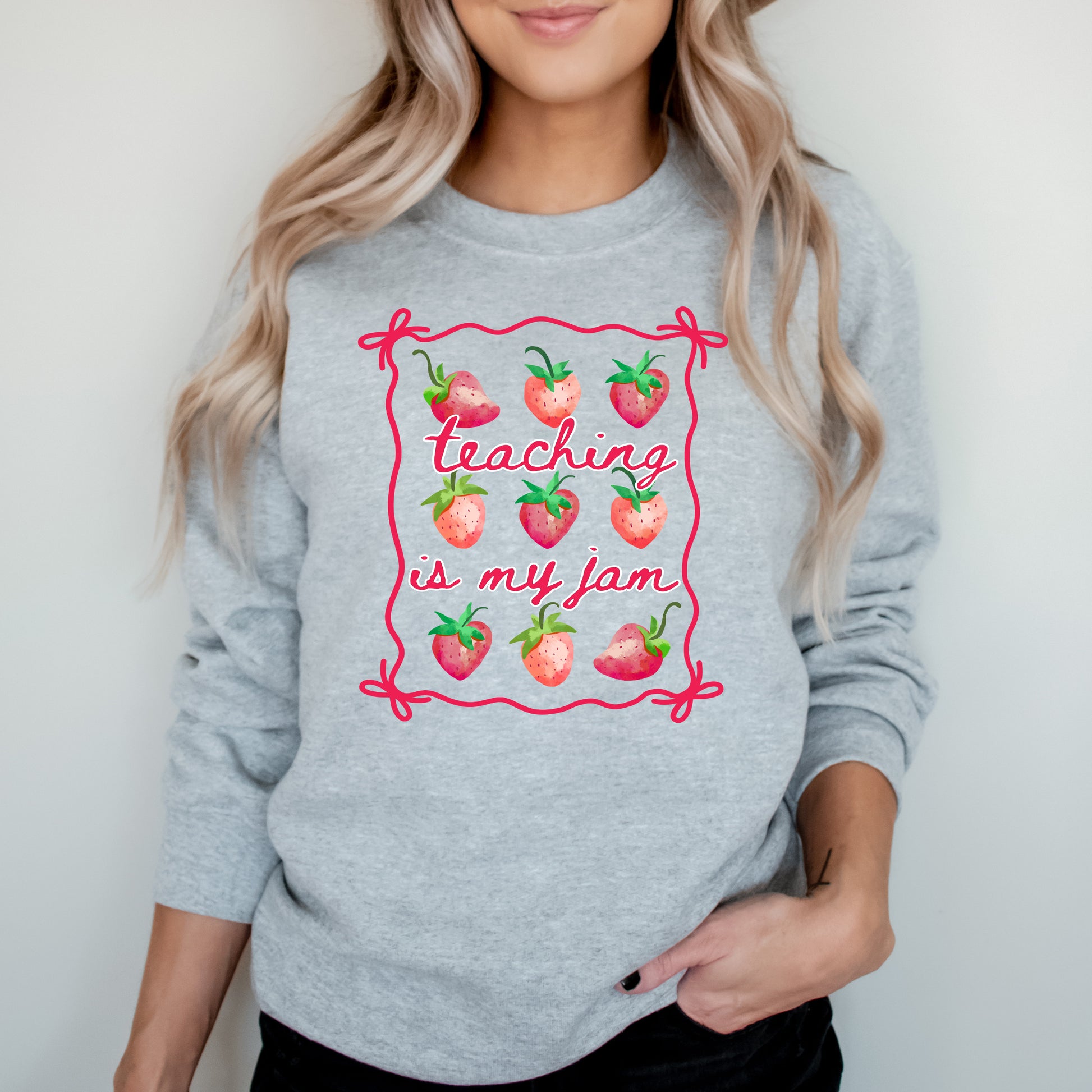 Person wearing a gray sweatshirt with 'Teaching is my jam' design.