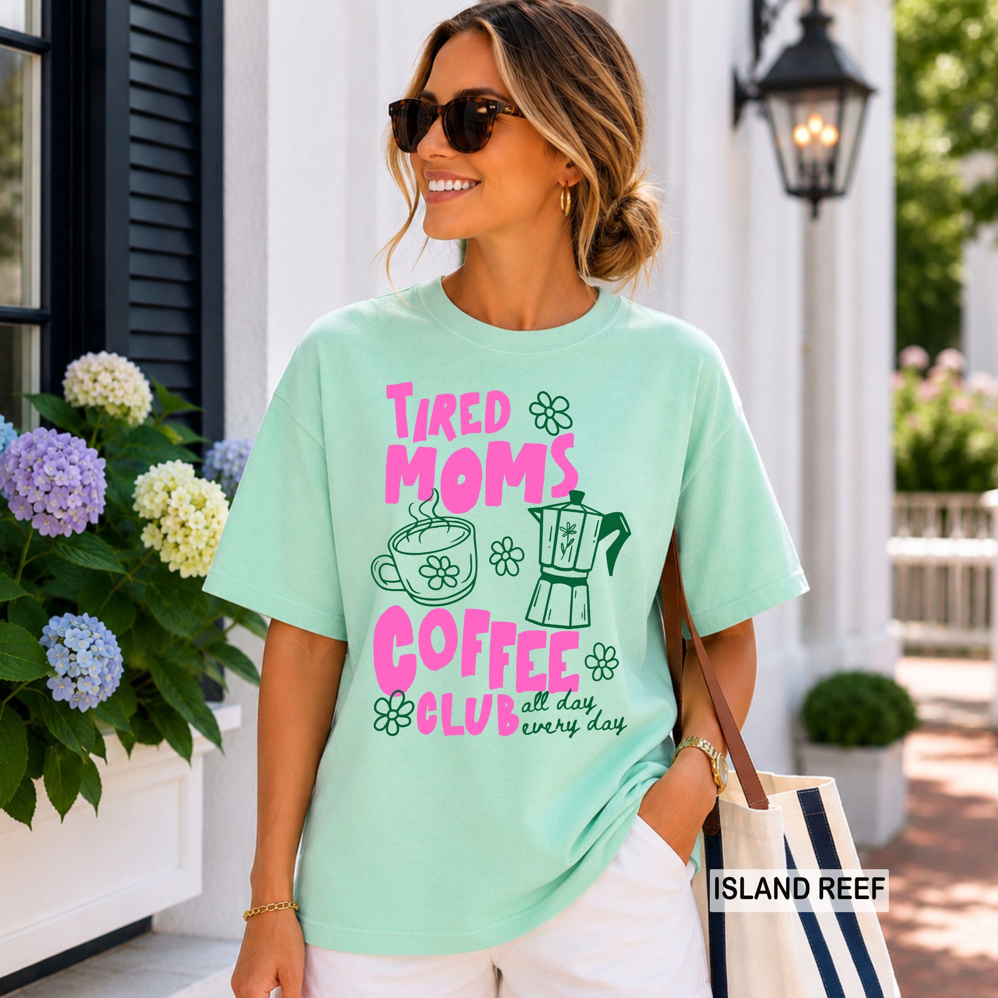 Woman wearing a light green t-shirt with text and graphics, standing outdoors.
