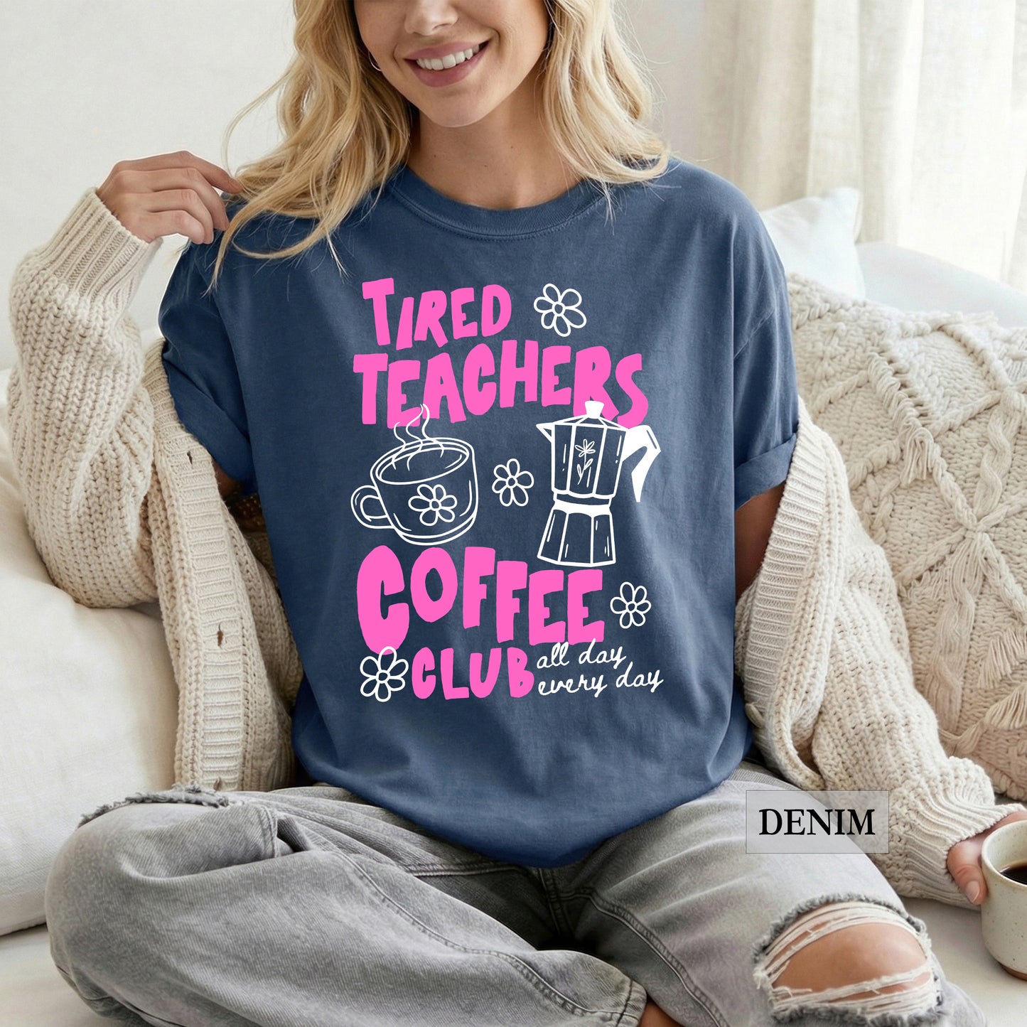 Woman wearing a denim shirt with 'Tired Teachers Coffee Club' design, sitting on a couch.