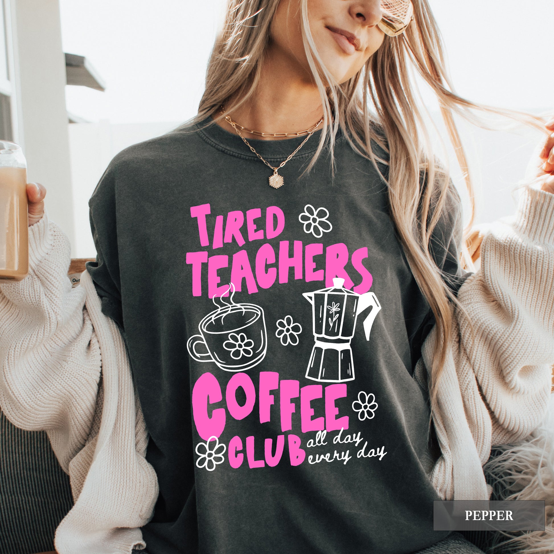 Person wearing a black sweatshirt with 'Tired Teachers Coffee Club' text and graphics.