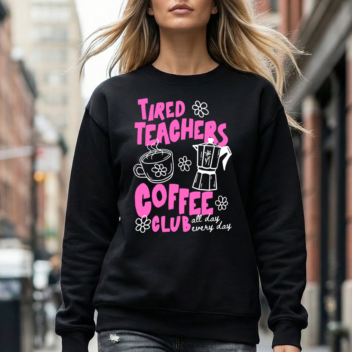 Person wearing a black sweatshirt with pink text and graphics on a city street.