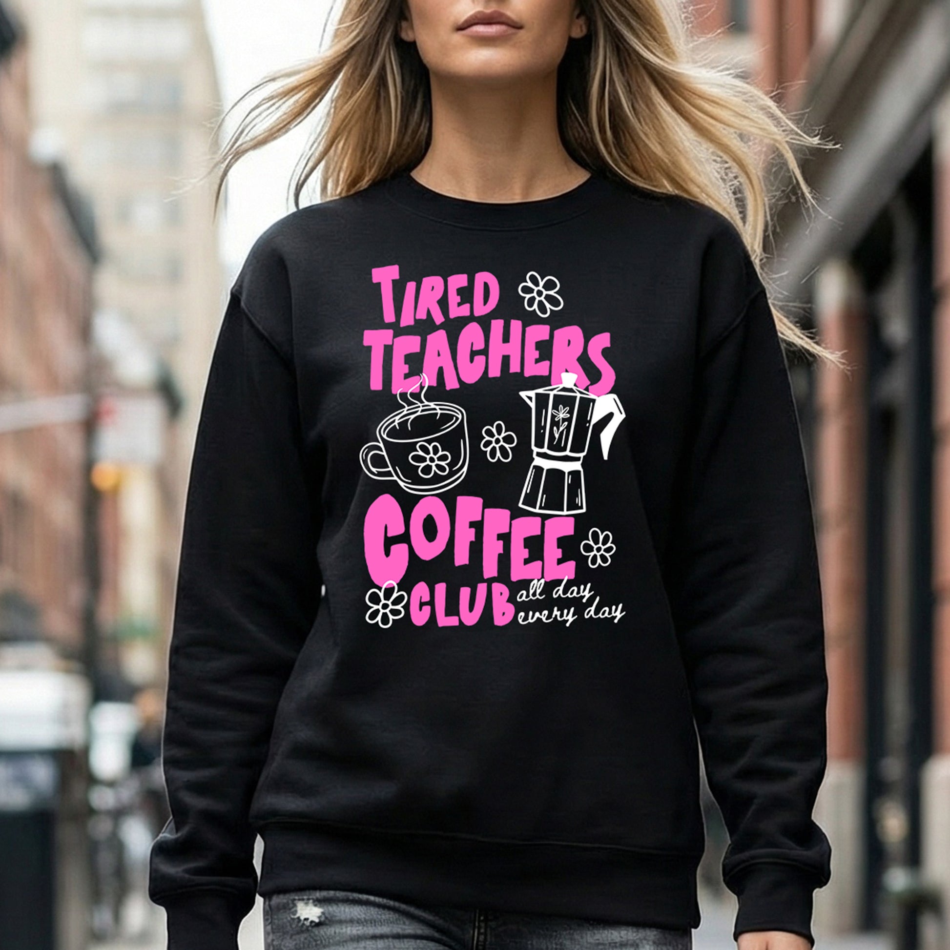 Person wearing a black sweatshirt with pink text and graphics on a city street.