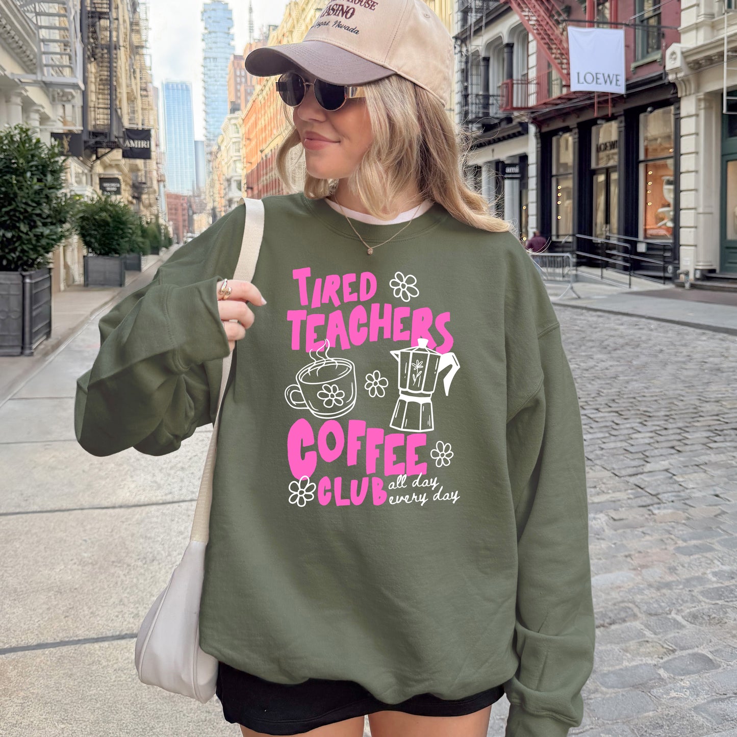 Woman wearing a green sweatshirt with text and graphics on a city street.