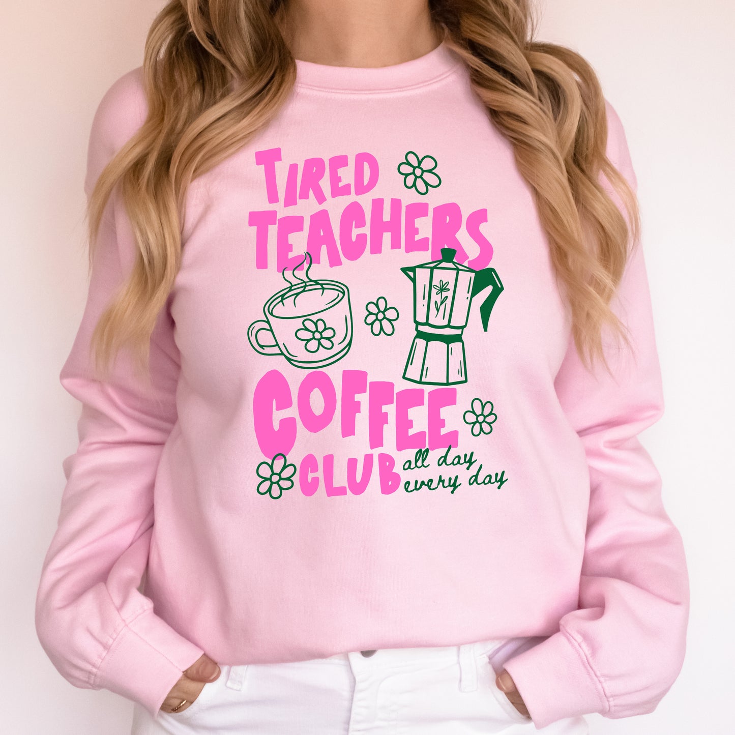 Pink sweatshirt with 'Tired Teachers Coffee Club' text and graphics on a plain background