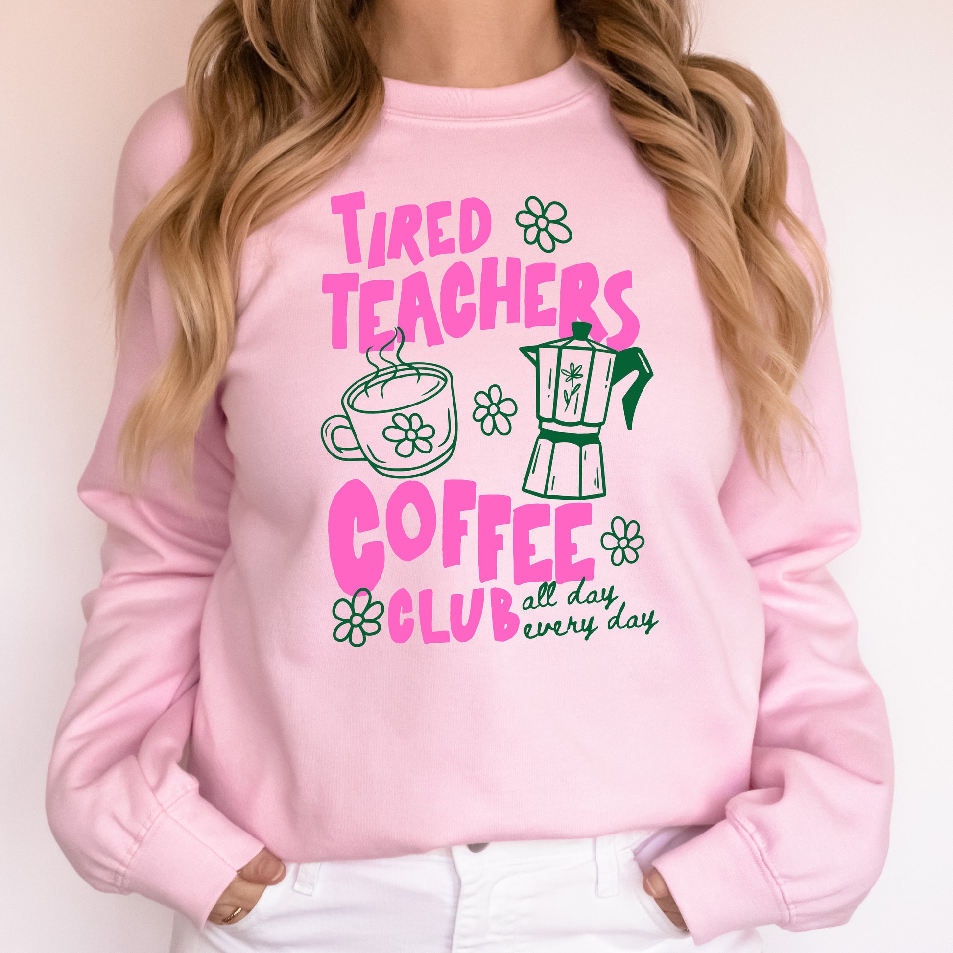 Pink sweatshirt with 'Tired Teachers Coffee Club' text and graphics on a plain background