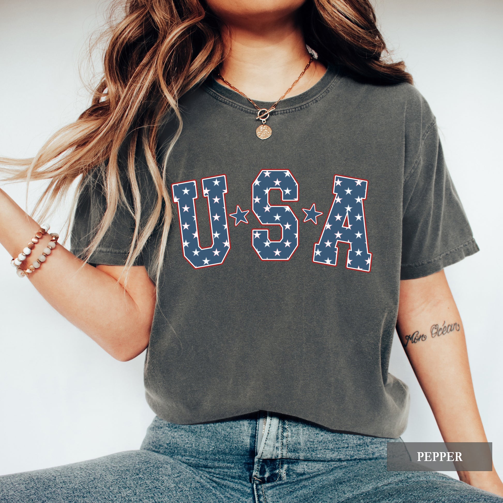 Person wearing a gray t-shirt with 'USA' printed in stars and stripes design.