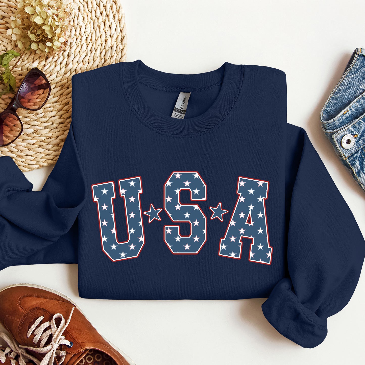 Navy blue sweatshirt with 'USA' design on a white surface with accessories.