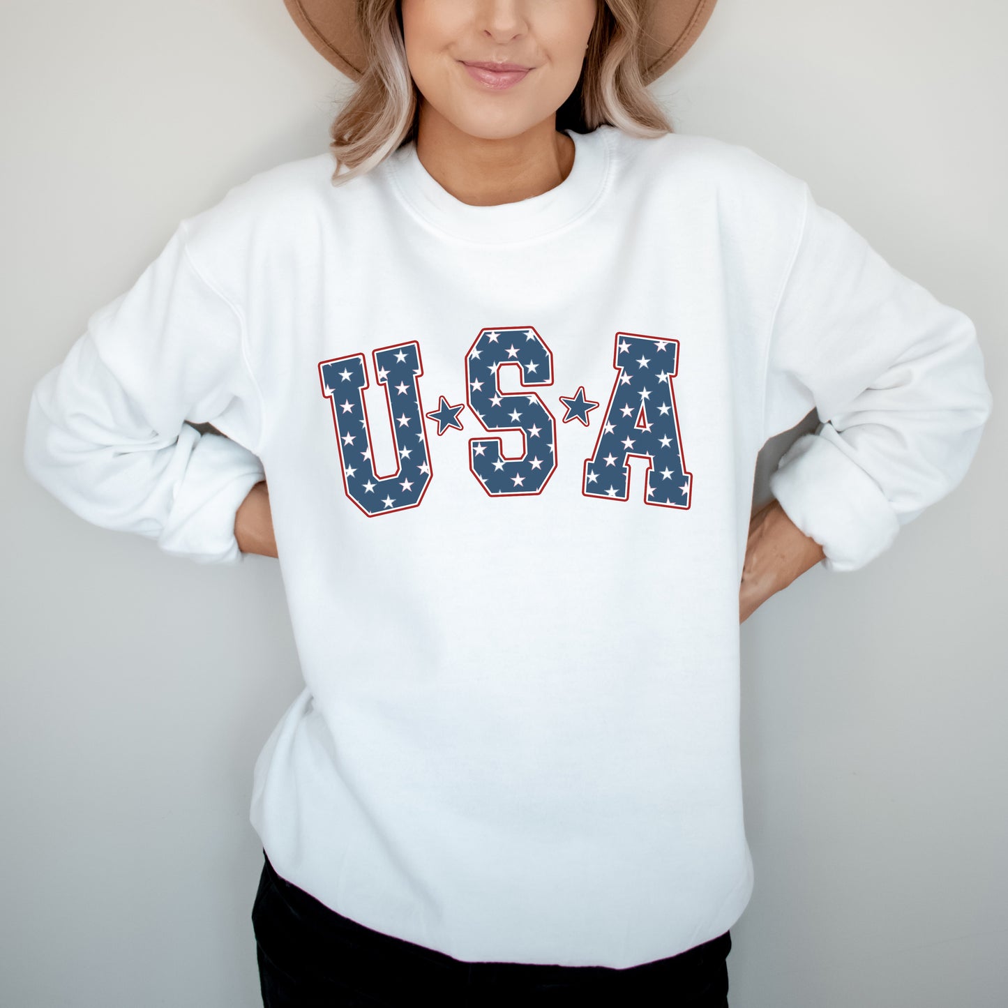 Person wearing a white sweatshirt with 'USA' text in star pattern on a plain background