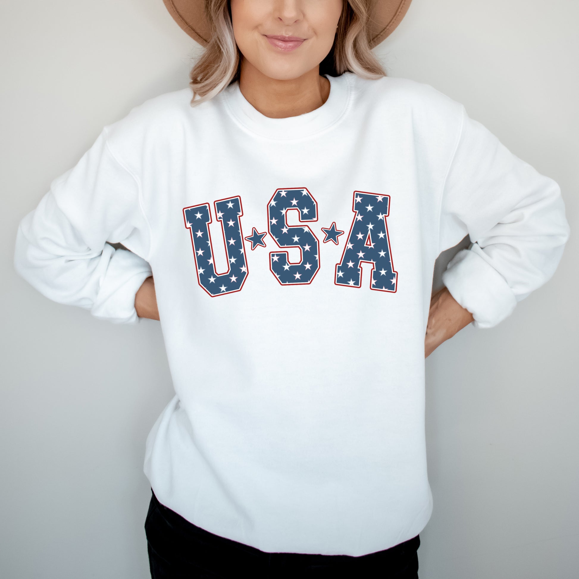 Person wearing a white sweatshirt with 'USA' text in star pattern on a plain background