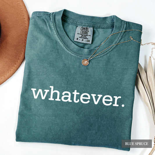 A folded slate blue spruce t-shirt with the word 'whatever.' printed in white lowercase letters across the front.