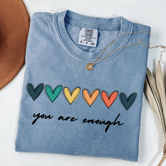 Blue t-shirt with rainbow hearts and 'you are enough' text on a white background